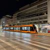 A street car zooms by at night in Athens