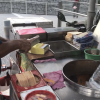 An ice-cream man is chopping up ice-cream for an ice-cream sandwich 