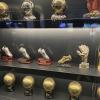 Here is a collection of trophies in the shape of the gear used by players; it includes cleats from players like Ronaldo, a goalkeeper’s glove, and some soccer balls