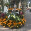 A catrina made of paper mache, surrounded by marigolds