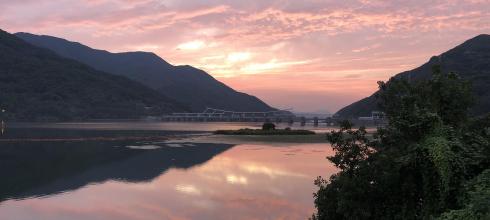 A sunset view of a dam and a reservoir.