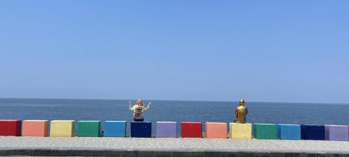 Sitting with a statue at the Jeju rainbow coastal road
