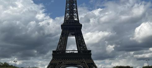 The Eiffel Tower is surrounded by large areas of grass that people hang out in and have picnics on. 