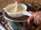 Putting halušky batter through strainer into boiling water
