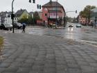 The ground is wet from the rain, and the wind has blown the leaves all over the sidewalk
