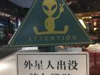 A sign outside a coffee shop, which translates to: If an alien roams about, please don't trample them