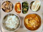 A typical Korean school lunch meal consisting of kimchi fish cake soup, sticky barley rice, boiled pork, cubed radish kimchi, seasoned cucumber chili and Korean melon (photo credit: koreanlunches.com)