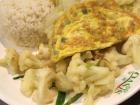 An omlette, along with large portions of rice and vegetables in the dining hall