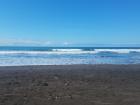 Dark sand beach and mid-rise waves in Playa Jacó, Puntarenas Province, Costa Rica