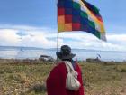 An Aymara man in the Andean region holding the indigenous Bolivian flag that represents the diversity