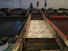 Fabric being printed with a floral pattern using a screen printer