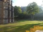 The corner of an old church stands above a grassy lawn in the morning light