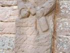 A worn sandstone sculpture depicting a man holding a bottle and a hammer