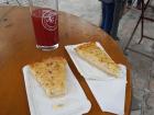 Two slices of onion cake sitting on a table next to a glass of juice. 