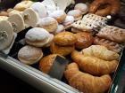 Rows of assorted pastries, donuts and cookies lining the display case of a grocery store bakery
