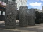 An art sculpture on the street between several buildings.