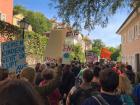 The middle of the march, a sign to the right reads "My kids also go through this air" 