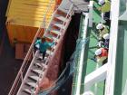 An expedition member boards the ship with deck crew looking on