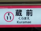 Station sign displaying the station name in Kanji (Chinese characters), hiragana (Japanese syllabary), and romaji (roman letters)