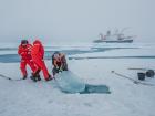 After ecosystem coordinator and scientist Alli Fong uses a chainsaw to cut a rectangle in the ice, ocean scientists Mario Hoppmann and Jacob Allerholt and Alli pull out the massive piece of ice