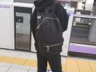 Woman with headphones waiting behind the "tenji blocks" and train barrier for the next train