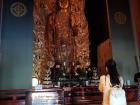 Woman praying in front of a golden Kannon statue in Hasedera Temple, Kamakura