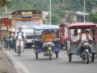  Buses, motorcycles, and tuk tuks are all present on a typical street in Iquitos