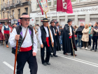 One shepherd carries a flag dedicated to the festival, and another carries the flag of León, a region in northwestern Spain