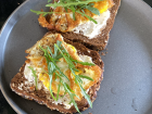 A typical breakfast for Goabaone featuring toasted bread, cream cheese, eggs and arugula 