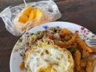 A typical lunch from the school canteen: rice, fruit, fried egg and grapbao muu with fried chicken on the side