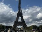 The Eiffel Tower is surrounded by large areas of grass that people hang out in and have picnics on. 