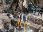 These orange machines are called Total Stations, and are high-tech equipment used to collect spatial data at excavations