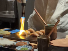 A sushi chef at a sushi omakase restaurant using a blowtorch to slightly roast the top of the nigiri sushi, giving it a nice torched taste!