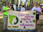 Livi holding a sign with another volunteer that says "Creamos espacios seguros en la naturaleza," or "We create safe spaces in nature"