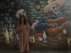 I am posing by a "Dia De Los Muertos" mural