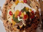 This is pizza made with pesto, cherry tomatoes, burrata, and sausage! 