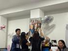 My coworkers helping one another to hang a portrait of our department