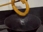 My aamaa pours some batter in her hand and draws a circle while squeezing the batter into the pan. The pan is specifically for sel roti, and the roti finishes frying almost instantly