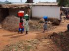 Malawian women carrying bins on their heads full of maize flour and other foods