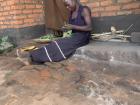 Woman preparing Nnkhwani (pumpkin leaves) on her front porch which she will then boil. Often this together with nsima will be all a family can afford for supper