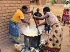 Two women making a BIG pot of nsima for their families