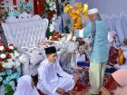 An elder presents bunga telur to the bride and groom in blessing