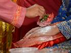 An elder sprinkling white powder on the bride’s hands during tepung tawar