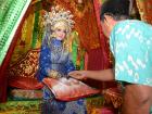 The bride embodies grace and beauty in her suntiang crown and intricate blue songket