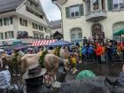 Cows adorned with flowers and cowbells proceed through the main street.