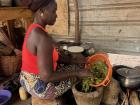 Maman adding the steamed kapokia leaves to the mortar