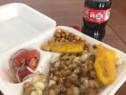 A traditional meal of roasted pork, hominy, fried plantains, and roasted corn.