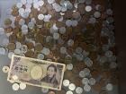 5000 yen bill on top of a pile of coins 