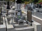 This grave has a stone lantern (left), flower cups (top middle), incense tray (bottom middle) and a name stone (right) for extra family members