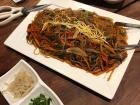 Japchae is a stir-fried dish of glass noddles, vegetables, and meat seasoned with soy sauce and sesame oil